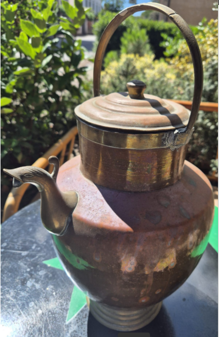 brocca in rame adagiata su tavolino 