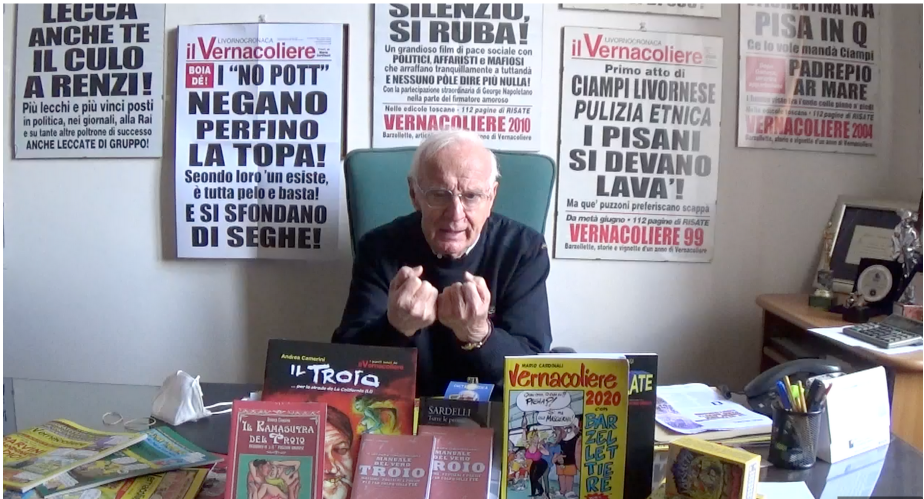 il direttore del Vernacoliere si appresta a speigare il numero di fine anno da dietro della sua scrivania e circondato dalle famose locandine con titoli provocatori come lecca anche te il cuolo di Renzi i no pott negano perfino la topa silenzio si ruba Pisa in Q e via dicendo