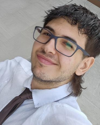 Ecco Gianluca che inforca il suo sorriso e i suoi occhiali sguardo intelligente e abbigliamento elegante vestito di camicia bianca e cravatta scura