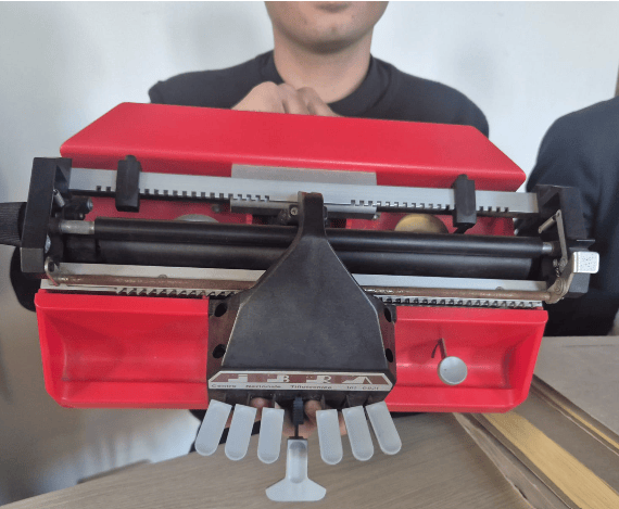 una stampante braille con i suoi tipici sei tasti per la scrittura in rilievo dei sei punti nel reticolo rettangolare e il tasto centrale per il vuoto o battuta musicale